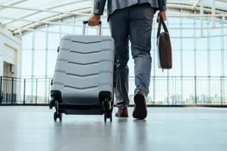 Foreign worker arriving in airport with suitcase and briefcase