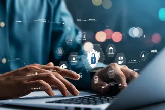Man typing at keyboard on laptop with cyber security icon overlays