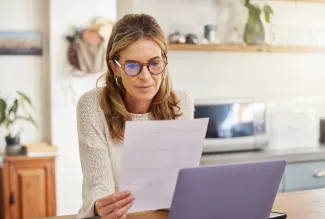 Woman reading document in front of laptop