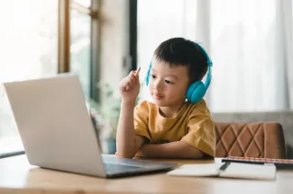 Child with headphones on looking at computer