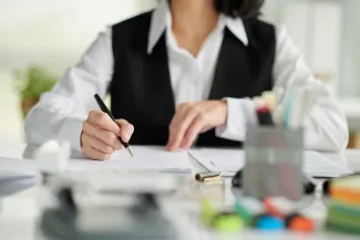 Woman at desk with pen in hand going over paperwork