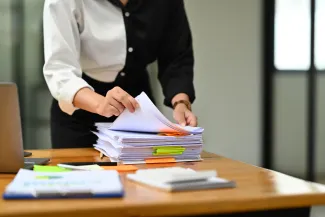 Woman with split colour top going through stack of paperwork