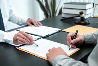 two people, one of whom is signing a contract