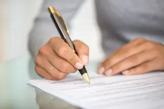 Person holding pen over paperwork