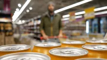 Man approaching yellow drink cans in supermarket