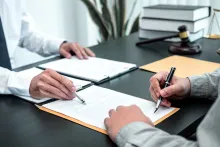 two people, one of whom is signing a contract